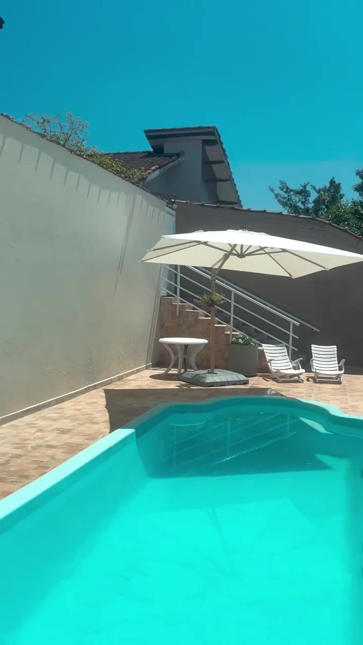 Piscina da Casa 1 vista do outro lado do terraço, com o guarda-sol aberto.