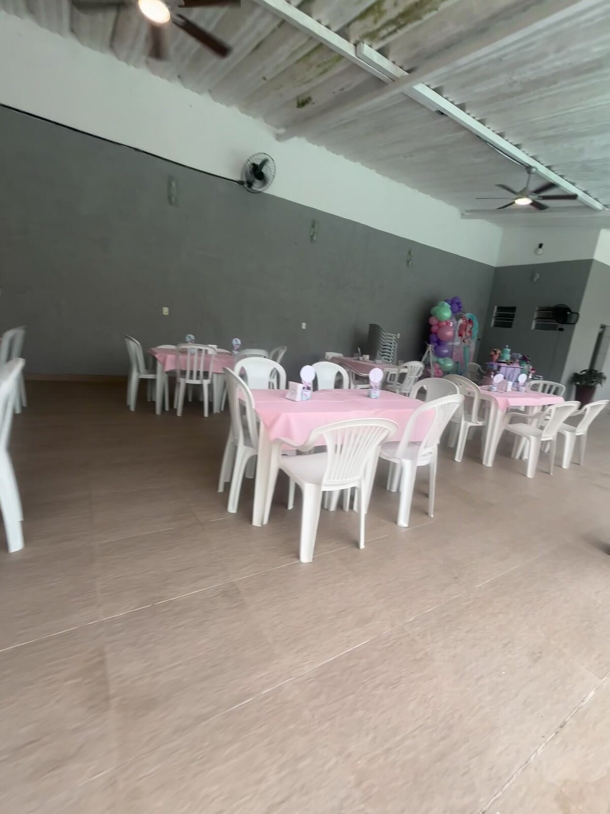 Área coberta da Casa 2 montada para uma festa, com mesas, cadeiras e decoração.